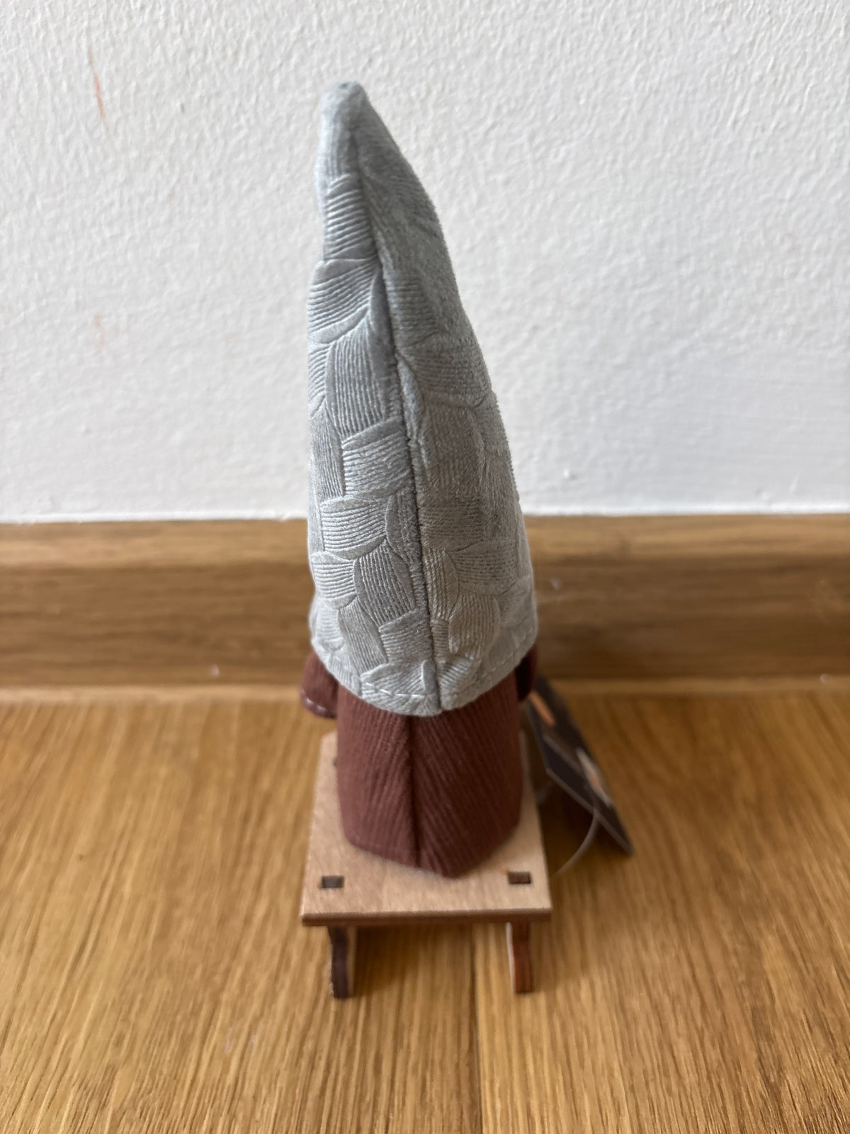 Deko kleiner Weihnachtszwerg auf einem Schlitten, graue Mütze