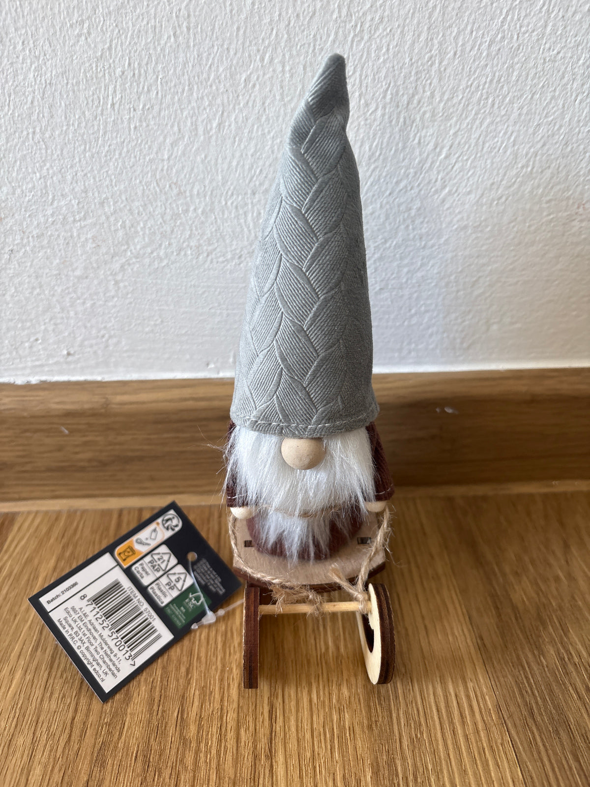 Deko kleiner Weihnachtszwerg auf einem Schlitten, graue Mütze